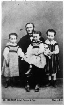 Louis-Prosper Claudel et ses trois enfants vers 1870.  Camille est la petite fille située à droite. Elle tient  une poupée.